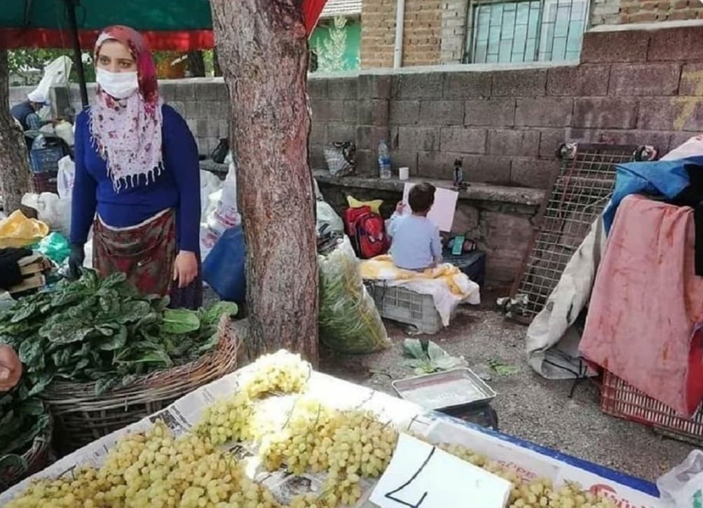 Annesiyle pazarda sebze satarken canlı derse katılan çocuk..